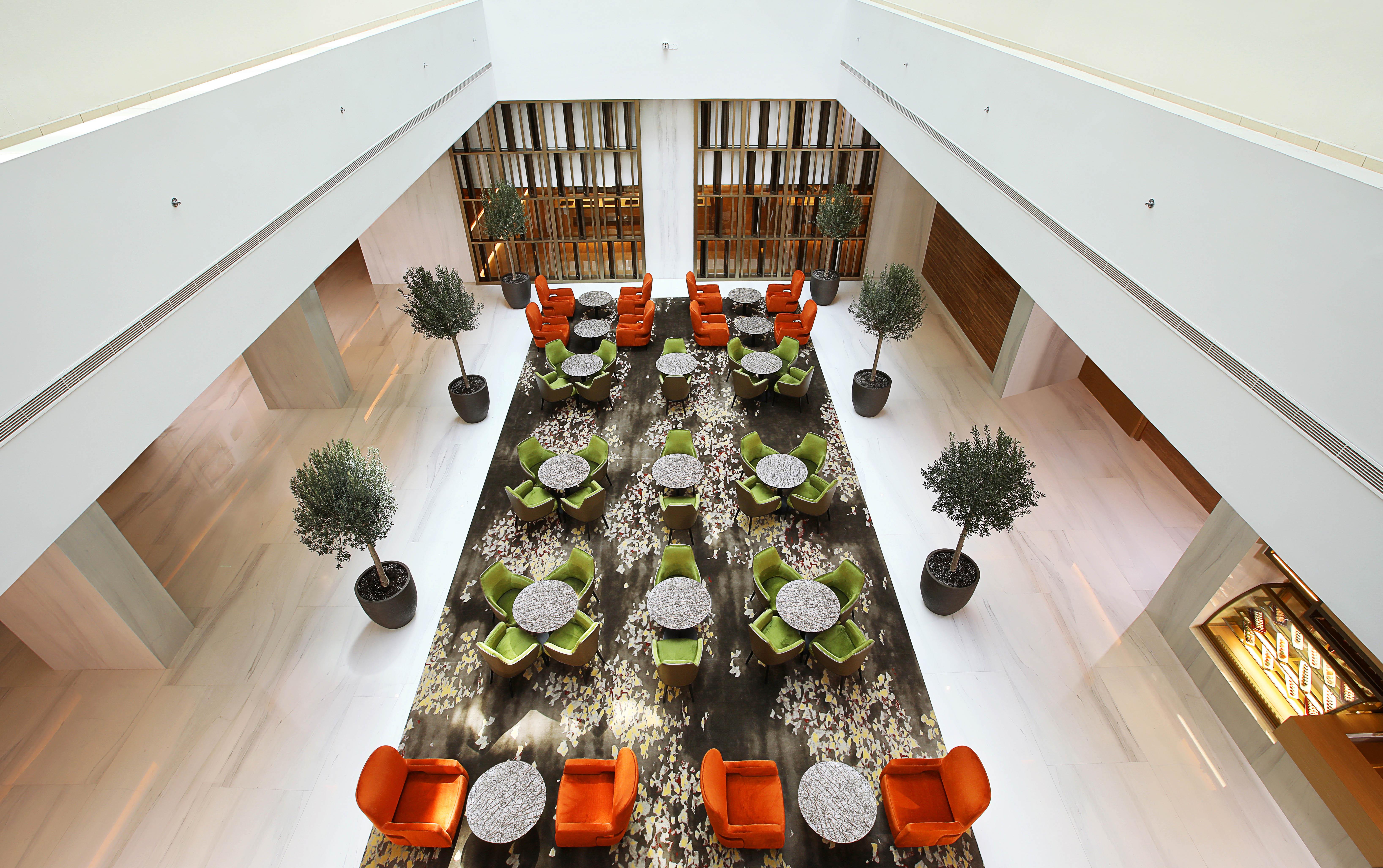 Grand Cosmopolitan Hotel Dubai Luaran gambar The photo showcases a modern interior space, likely a hotel or a lounge. The setting features a large, open area with a stylish arrangement of seating. 

There are vibrant orange and green chairs arranged around circular tables, providing a cozy atmo