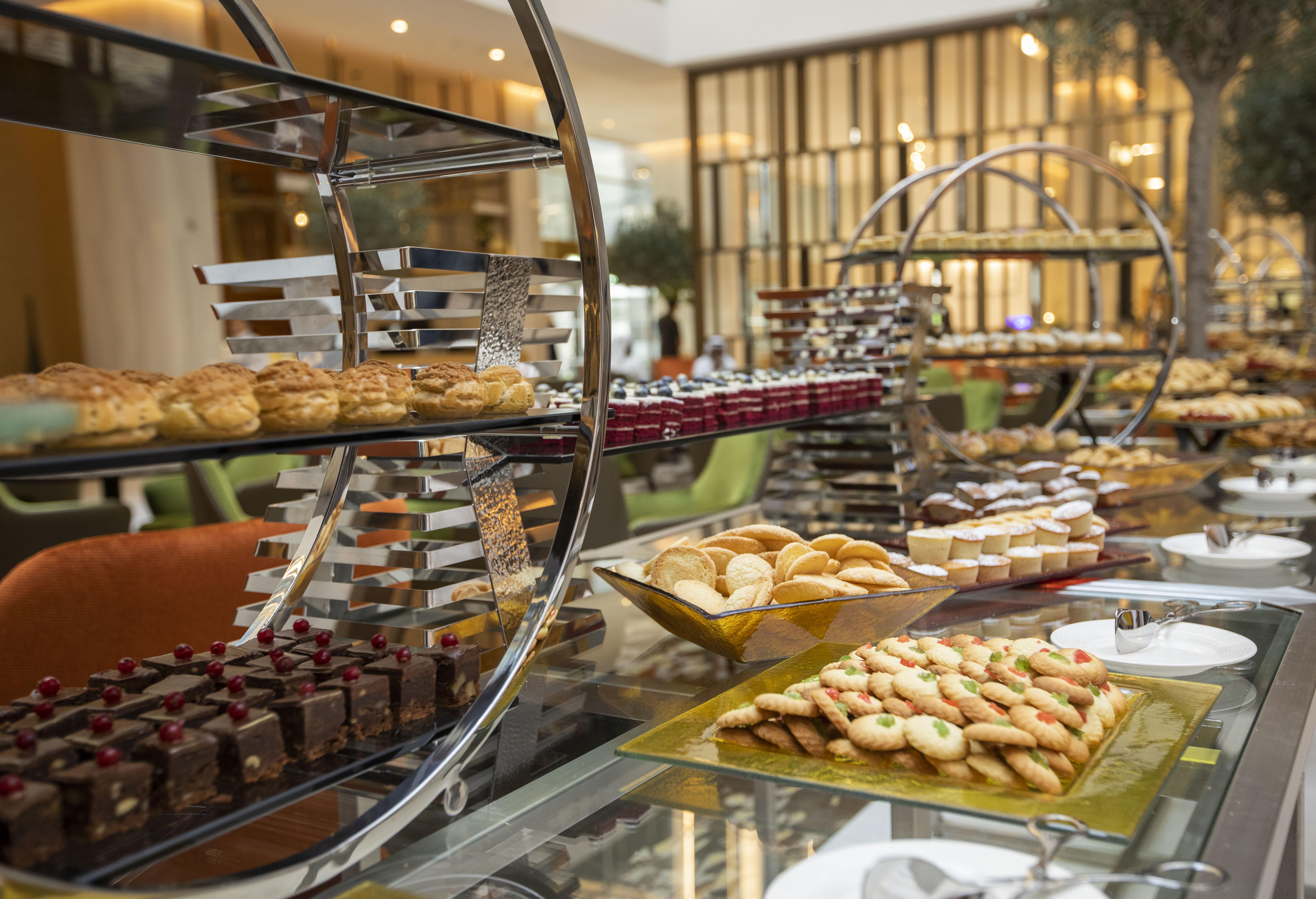 Grand Cosmopolitan Hotel Dubai Luaran gambar The photo showcases an elegant dessert display featuring a variety of baked goods. There are multiple tiers of treats, including pastries, cookies, and chocolates. On the lower tier, there appears to be an assortment of cookies arranged on a rectangu