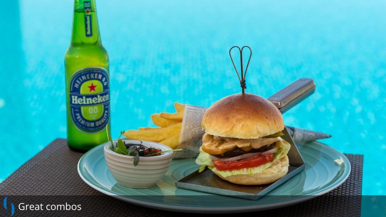 Grand Cosmopolitan Hotel Dubai Luaran gambar The photo features a delicious-looking meal consisting of a hamburger, accompanied by French fries and a small dish of sauce or dip. The hamburger is topped with lettuce, tomato, and what appears to be a grilled chicken patty, all held together by a 