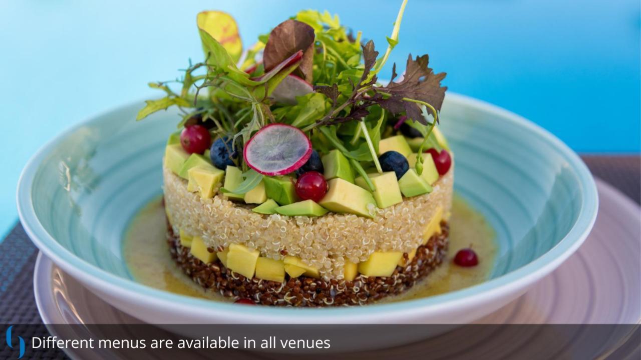 Grand Cosmopolitan Hotel Dubai Luaran gambar The photo features a beautifully arranged dish that resembles a layered salad or a savory cake. It consists of various fresh ingredients, including avocado, diced mango, blueberries, and radishes, all artfully layered to create an appealing presentat