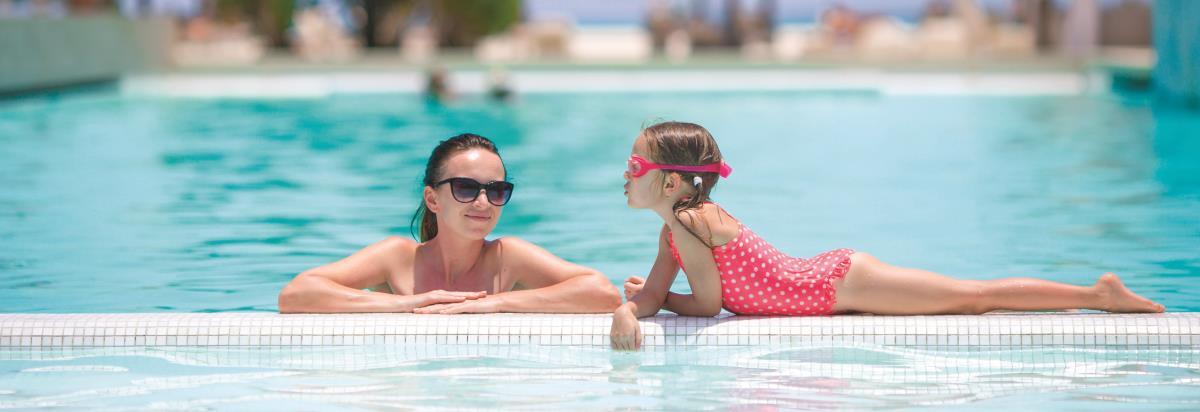 Grand Cosmopolitan Hotel Dubai Luaran gambar The photo shows a woman and a girl in a swimming pool. The woman is wearing sunglasses and appears relaxed, leaning on the edge of the pool. The girl, wearing a pink swimsuit with white polka dots and swim goggles, is playfully leaning over the edge 